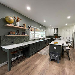 A kitchen interior features a long counter, center island with seating, and floor-to-ceiling cabinets