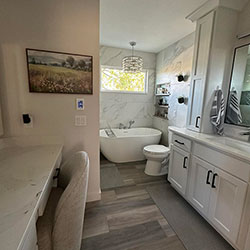 A bathroom interior featuring white cabinetry with black handles