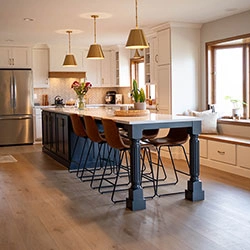A kitchen with cabinets along the walls and a long center island that features cabinets and bar seating