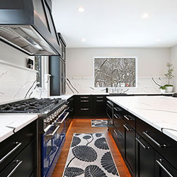 A kitchen interior with black cabinetry and white countertops lining two walls