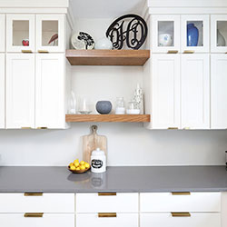 White cabinetry that incorporates floating shelves and glass panes to showcase kitchen decor