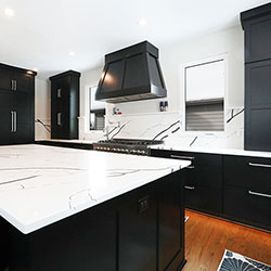 Black cabinets and white marble-style countertops line a kitchen interior