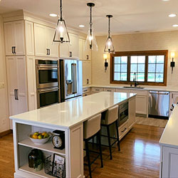 A kitchen interior with white cabinets features a center island that includes seating and a microwave