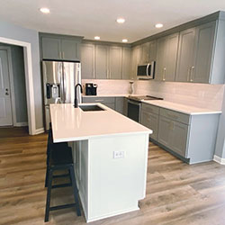 A kitchen interior with gray cabinetry and a white center island