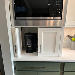 A cabinet area on a counter serves as a storage area for a coffee maker