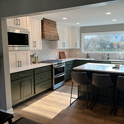 A kitchen interior with dark green and white cabinets includes a large window looking outside
