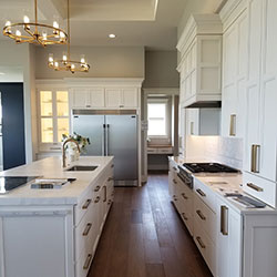 A kitchen interior features all-white cabinetry along the walls and center island
