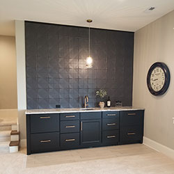 A sink, counter, and floor cabinets that line a textured wall on the interior of a home