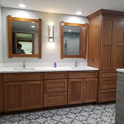 A bathroom interior with natural wood cabinetry and a counter with two sinks