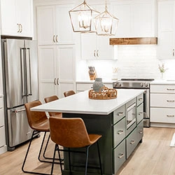 A kitchen interior features a center island with sliding drawers and a microwave mounted inside.