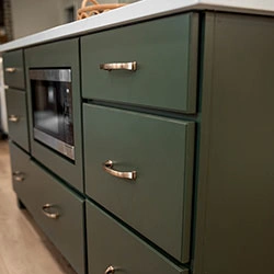 A center island with sliding drawers and a microwave mounted inside.